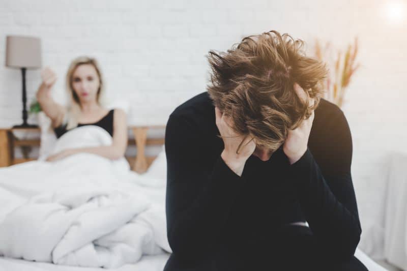 man stressed in relationship. angry woman in bed